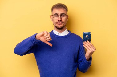 Young computer man isolated on yellow background showing a dislike gesture, thumbs down. Disagreement concept.