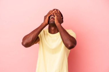 Pembe arka planda izole edilmiş genç Afro-Amerikalı adam mutlu bir şekilde ellerini başının üstünde tutarak gülüyor. Mutluluk kavramı.