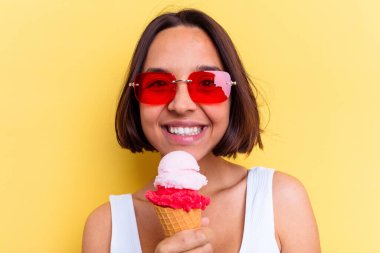 Sarı arka planda izole edilmiş dondurma tutan melez bir kadın.