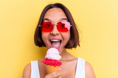 Sarı arka planda izole edilmiş dondurma tutan melez bir kadın.