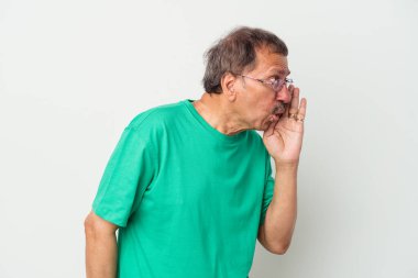 Middle aged indian man isolated on white background is saying a secret hot braking news and looking aside