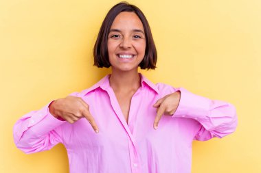 Sarı arka planda izole edilmiş genç melez kadın parmakları aşağıda, olumlu hisler içinde..