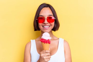 Sarı arka planda izole edilmiş dondurma tutan melez bir kadın.
