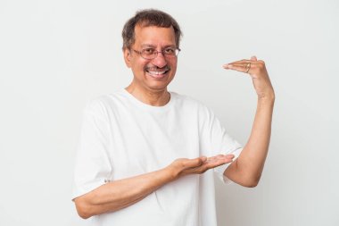 Middle aged indian man isolated on white background holding something little with forefingers, smiling and confident.
