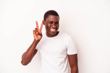 Beyaz arka planda izole edilmiş genç bir Afrikalı Amerikalı zafer işareti gösteriyor ve gülümsüyor..