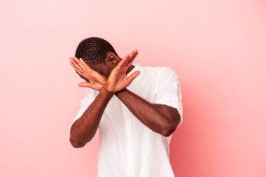 Genç Afrikalı Amerikalı adam pembe arka planda izole edilmiş iki kolu çapraz tutuyor, inkar kavramı.