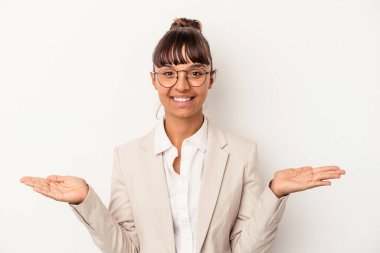 Beyaz arka planda soyutlanmış genç melez kadın kollarıyla ölçeği yapıyor, mutlu ve kendinden emin hissediyor..