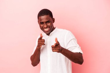 Genç Afro-Amerikalı adam pembe arka planda izole edilmiş neşeli gülümsemeler ön tarafı işaret ediyor..