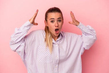 Pembe arka planda izole edilmiş genç Rus kadın mutlu bir şekilde gülüyor ve ellerini karnının üstünde tutarak eğleniyor..