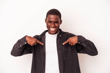 Beyaz arka planda izole edilmiş genç bir Afro-Amerikan erkeği parmağını gösterip gülümseyerek şaşırdı..