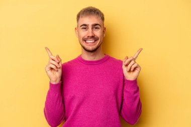 Sarı arka planda izole edilmiş genç beyaz adam farklı kopya alanlarını gösteriyor, birini seçiyor, parmağıyla gösteriyor..