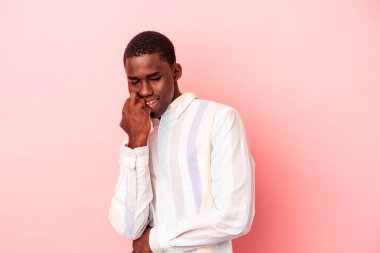 Pembe arka planda izole edilmiş genç bir Afrikalı Amerikalı. Rahatlamış bir şekilde fotokopi odasına bakıyor..