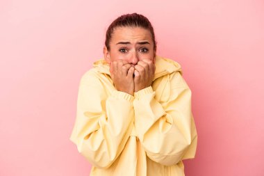 Pembe arka planda izole edilmiş, tırnak yiyen, gergin ve endişeli genç Rus kadın..