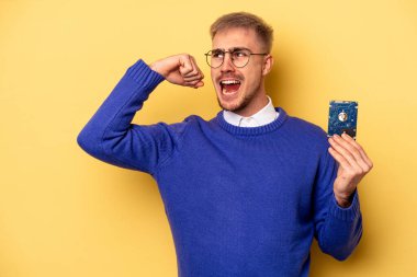 Young computer man isolated on yellow background raising fist after a victory, winner concept.