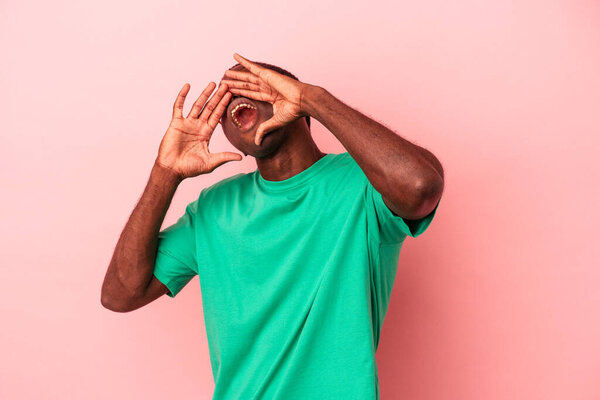 Young African American man isolated on pink background shouting excited to front.