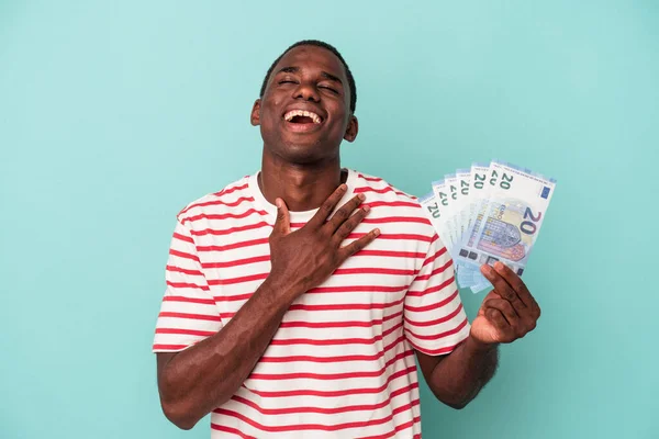 Молодой Афроамериканец Держащий Банкноты Синем Фоне Громко Смеется Держа Руку — стоковое фото