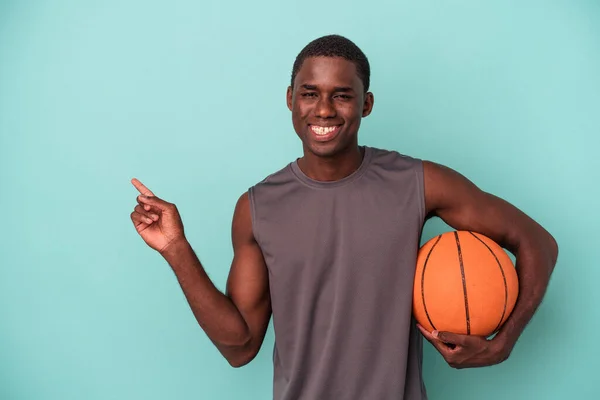 Joven Afroamericano Jugando Baloncesto Aislado Sobre Fondo Azul Sonriendo Señalando — Foto de Stock