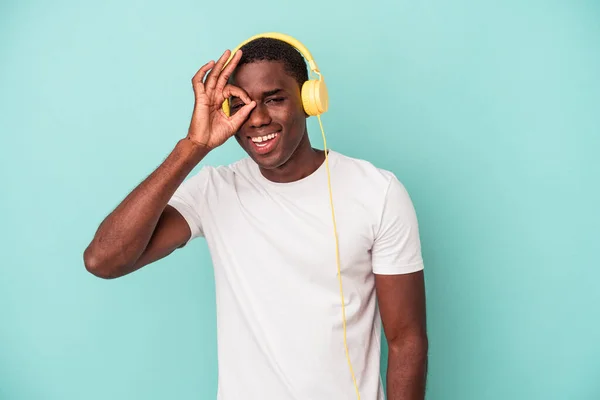 Joven Afroamericano Hombre Escuchando Música Aislado Fondo Azul Emocionado Mantener —  Fotos de Stock