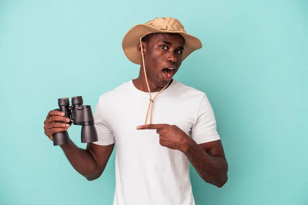Молодий Афроамериканець Тримає Бінокль Ізольованим Синьому Фоні Вказує Бік — стокове фото