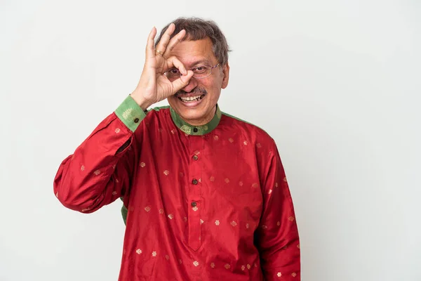 Senior indian man wearing a Indian costume isolated on white background excited keeping ok gesture on eye.