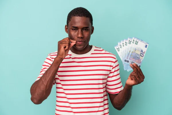 Mladý Afroameričan Drží Bankovky Izolované Modrém Pozadí Prsty Rtech Drží — Stock fotografie