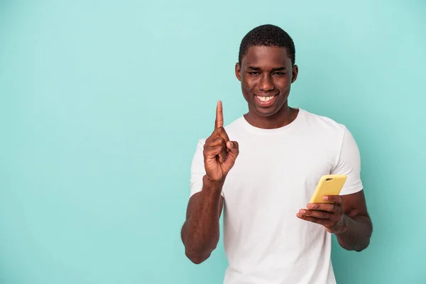 Young African American Man Holding Mobile Phone Isolated Blue Background — Stock Photo, Image