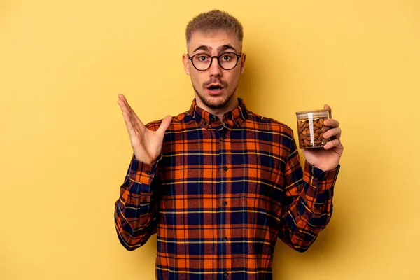 Young Caucasian Man Holding Almond Jar Isolated Yellow Background Surprised — Foto de Stock