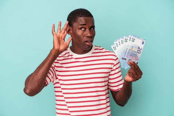 Молодой Афроамериканец Держит Банкноты Синем Фоне Пытаясь Выслушать Сплетни — стоковое фото