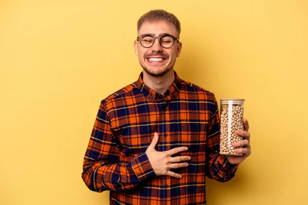 Young Caucasian Man Holding Chickpeas Isolated Yellow Background Laughing Having — Photo