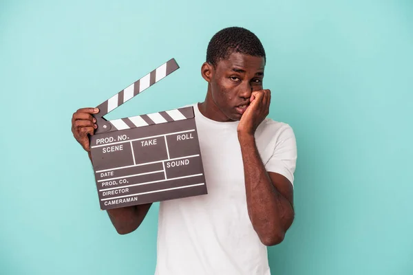 Young African American Man Holding Clapperboard Isolated Blue Background Biting — Stock Photo, Image