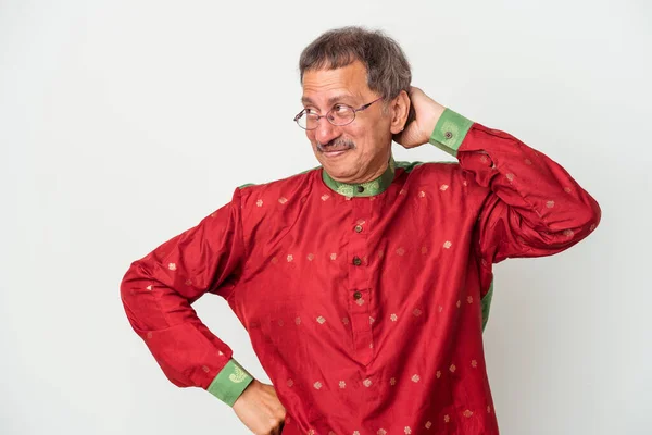 Senior indian man wearing a Indian costume isolated on white background touching back of head, thinking and making a choice.