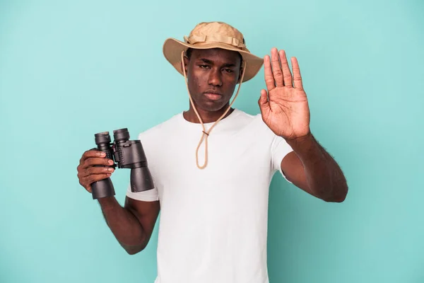 Молодий Афроамериканець Тримає Бінокль Ізольованим Синьому Фоні Витягнутою Рукою Показує — стокове фото