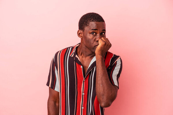 Young African American man isolated on pink background biting fingernails, nervous and very anxious.