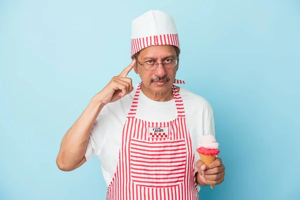 Senior american ice cream man holding an ice cream isolated on blue background pointing temple with finger, thinking, focused on a task.