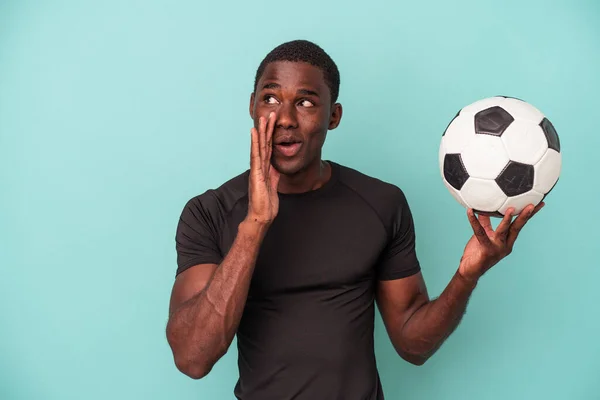Młody Afroamerykanin Grający Piłkę Nożną Niebieskim Tle Mówi Sekretną Wiadomość — Zdjęcie stockowe