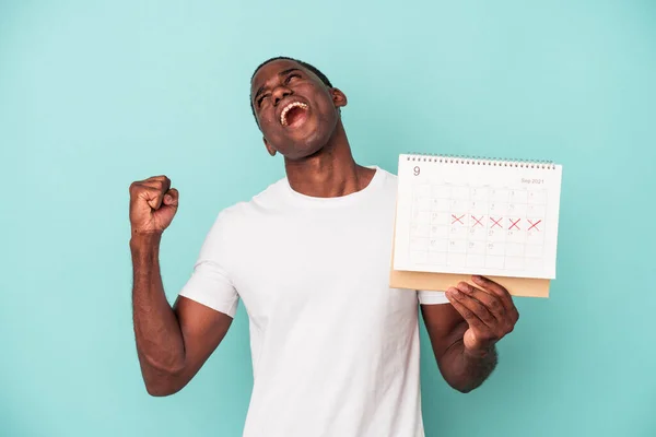 Ung Afroamerikansk Man Håller Kalender Isolerad Blå Bakgrund Höja Näve — Stockfoto