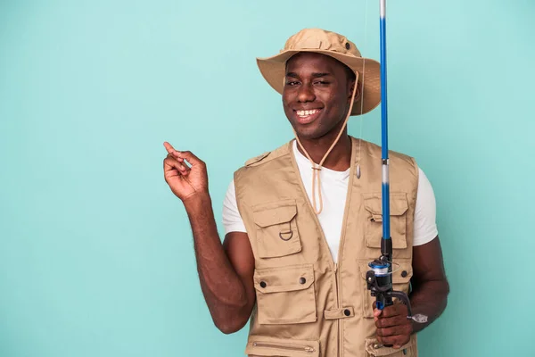 Молодий Афроамериканський Рибалка Тримає Стрижень Ізольований Синьому Фоні Посміхається Вказує — стокове фото