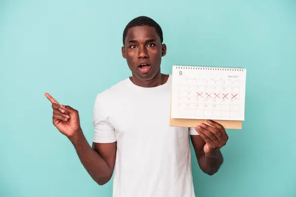 Mladý Afroameričan Drží Kalendář Izolovaný Modrém Pozadí Ukazuje Strany — Stock fotografie