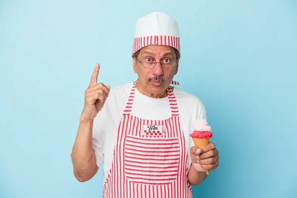 Senior american ice cream man holding an ice cream isolated on blue background having some great idea, concept of creativity.
