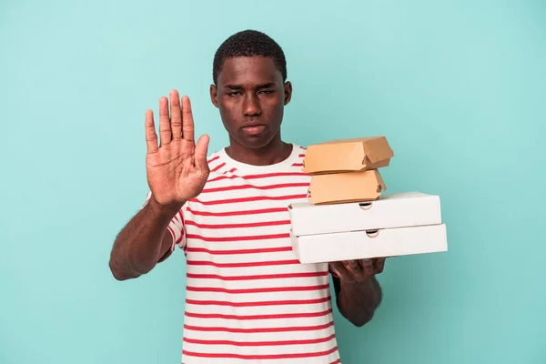 Mladý Afroameričan Drží Pizzy Hamburgery Izolované Modrém Pozadí Nataženou Rukou — Stock fotografie