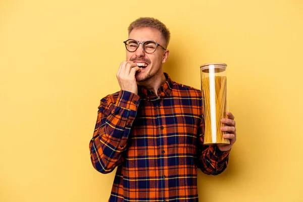 Young Caucasian Man Holding Spaghettis Jar Isolated Yellow Background Biting — Stock fotografie
