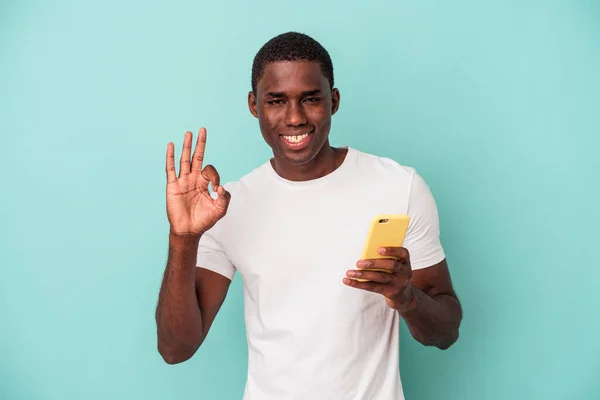 Young African American Man Holding Mobile Phone Isolated Blue Background — Stock Photo, Image