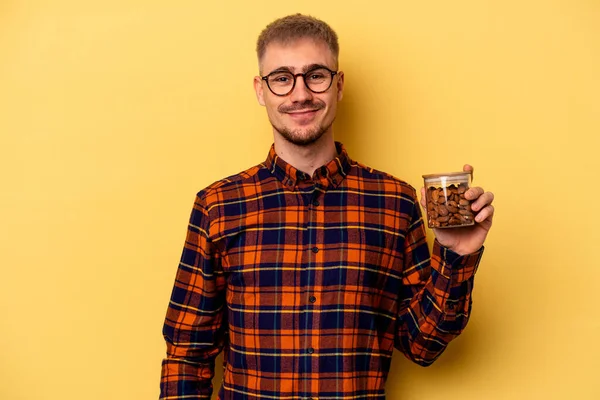 Young Caucasian Man Holding Almond Jar Isolated Yellow Background Happy — Zdjęcie stockowe