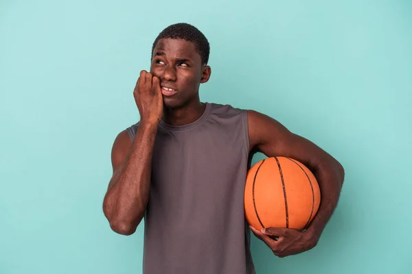 Jovem Afro Americano Jogando Basquete Isolado Fundo Azul Mordendo Unhas — Fotografia de Stock