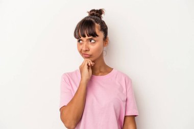 Beyaz arka planda izole edilmiş genç melez kadın şüpheli ve şüpheci bir ifadeyle yana bakıyor..