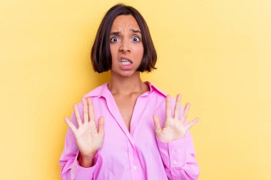 Sarı arka planda izole edilmiş genç melez bir kadın tiksinti gösteren birini reddediyor..