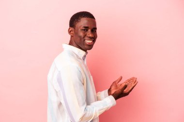 Pembe arka planda izole edilmiş genç Afro-Amerikalı bir adam. Elinde bir fotokopi odası var..