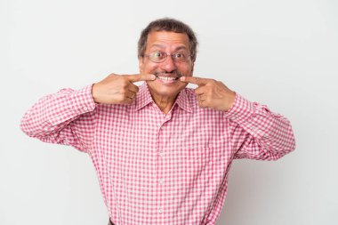 Middle aged indian man isolated on white background smiles, pointing fingers at mouth.