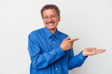 Middle aged indian man isolated on white background excited holding a copy space on palm.