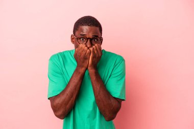 Genç Afrikalı Amerikalı bir adam pembe arka planda izole edilmiş tırnak yiyor, gergin ve çok endişeli..